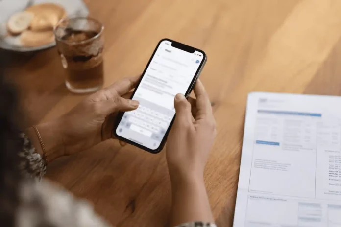 Salarié rédigeant une demande d'acompte sur salaire par email à côté de sa fiche de paie